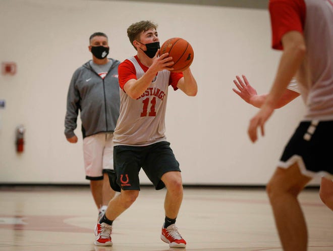 Dallas Center-Grimes head boys basketball coach Joel Rankin watches in the background as his son and senior guard Luke Rankin primes up a shot from three-point range during practice at Dallas Center-Grimes High School in Grimes on Wednesday, Jan. 7, 2021.